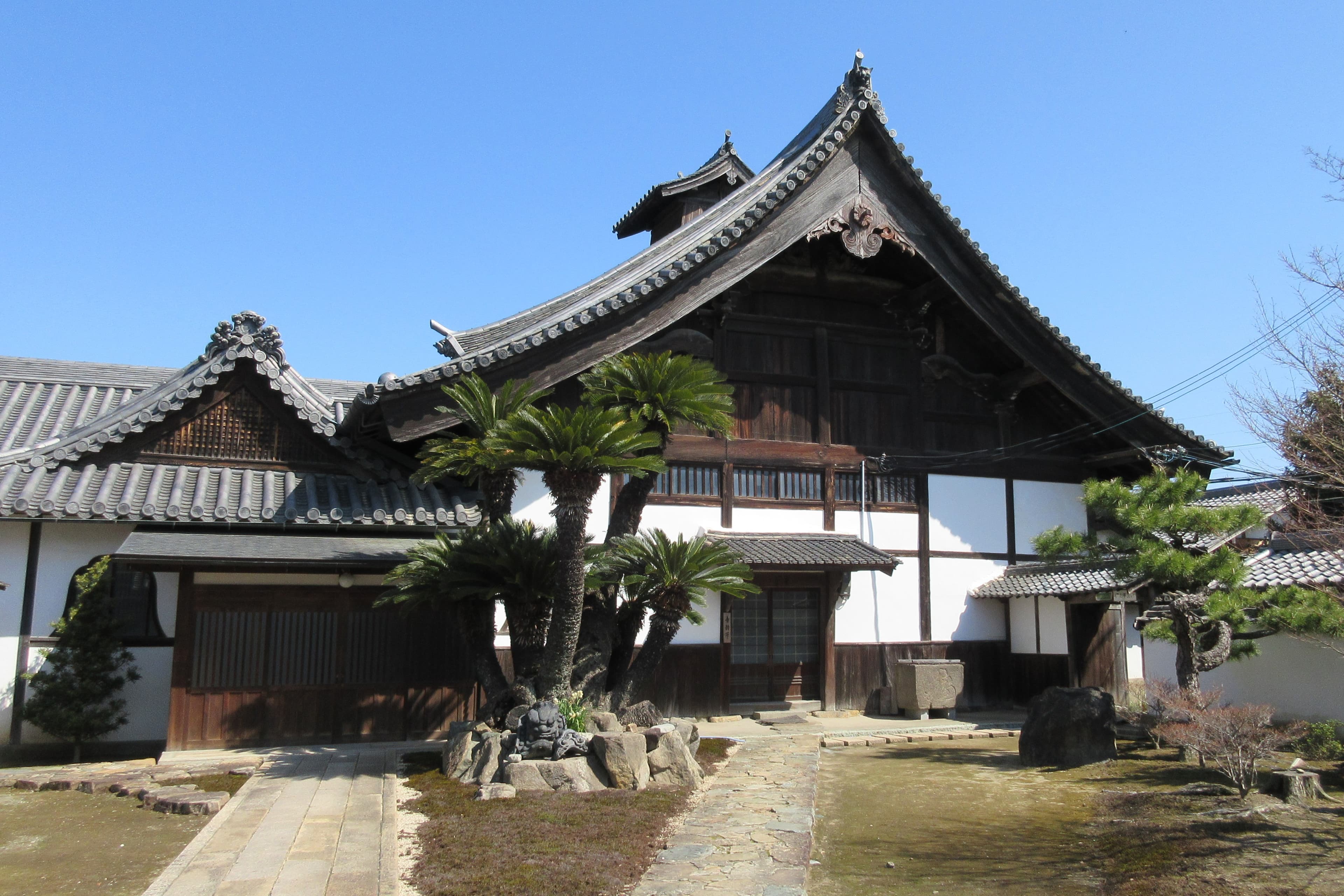 The tiled roof, wooden facade, and garden of Ryumon-ji Temple in Himeji